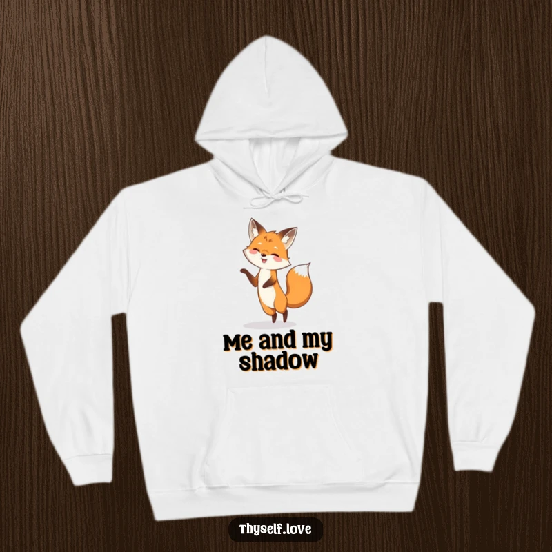 Funny hoodie depicting a smiling fox engaged in a whimsical dance with its shadow, symbolizing playful energy and lighthearted fun.